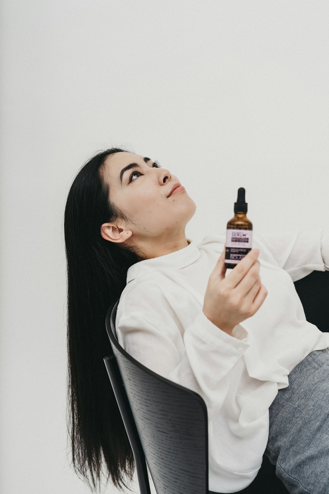 woman in white long sleeve shirt holding black bottle