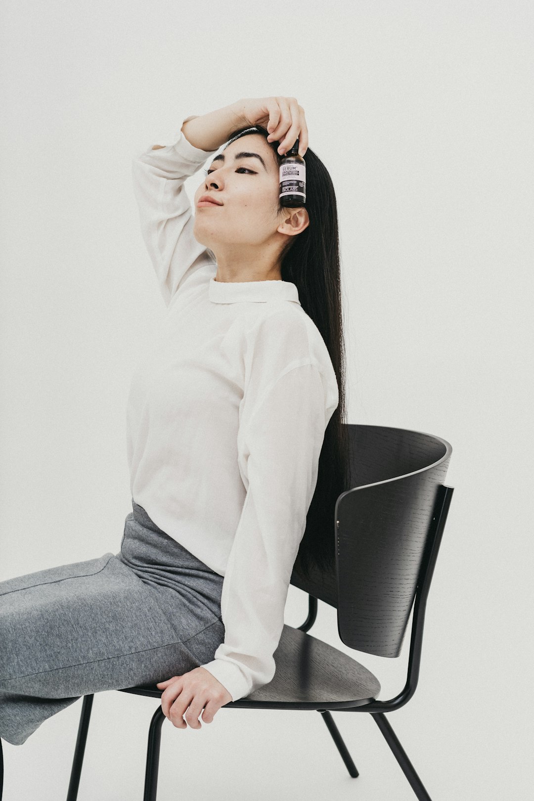 woman in white long sleeve shirt and blue denim jeans sitting on black chair