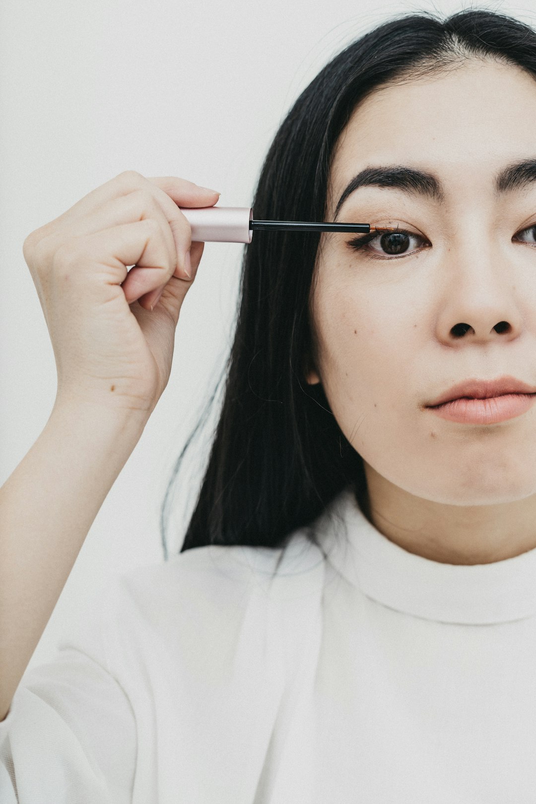 woman in white crew neck shirt holding black pen