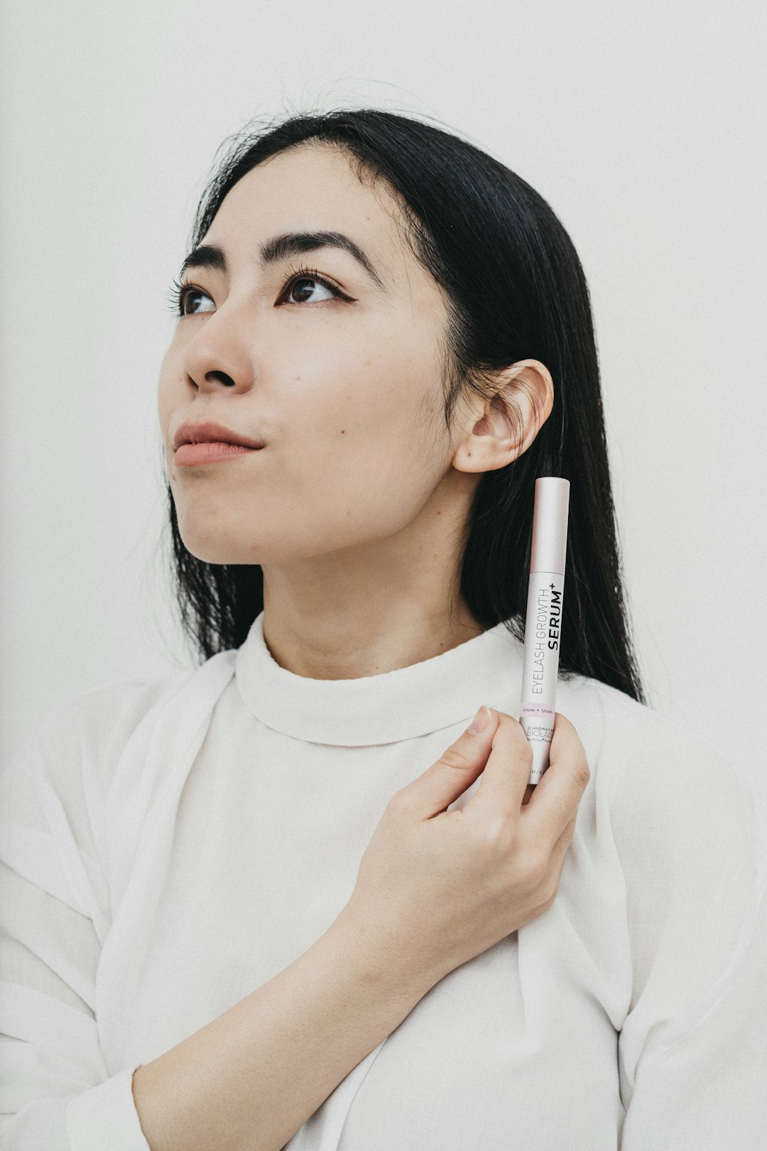 woman in white crew neck shirt holding white and black pen