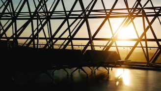 A quiet airport lounge bathed in soft evening light, with a lone figure lost in thought.