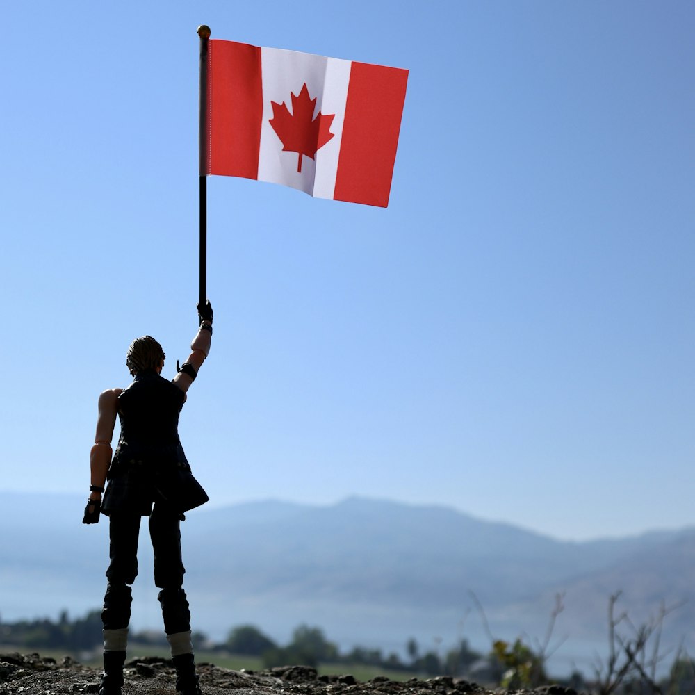 man holding flag of us a standing on rock during daytime