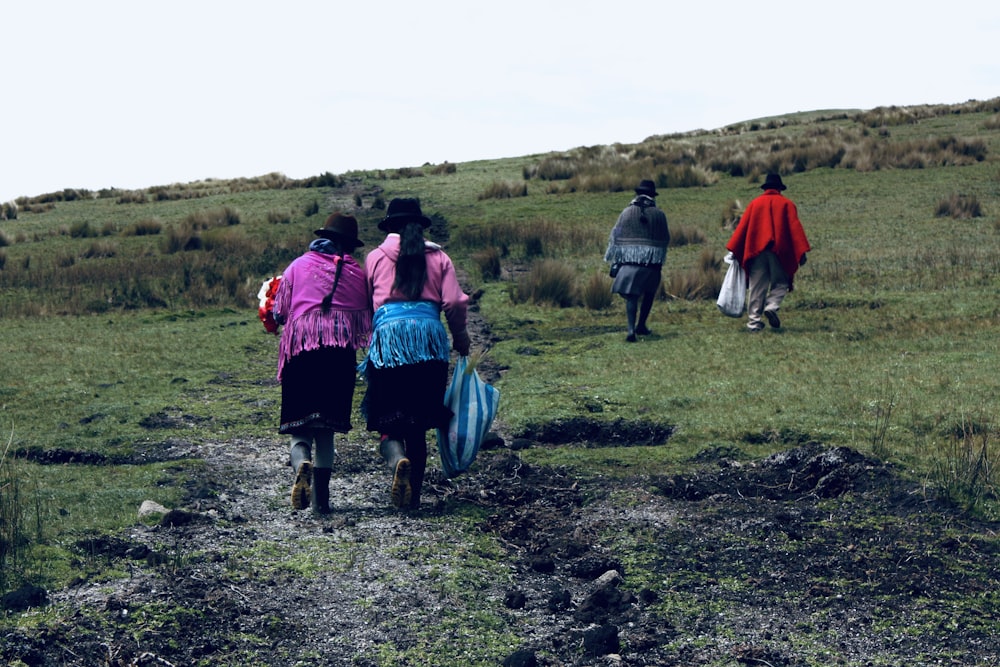 a group of people walking across a lush green field