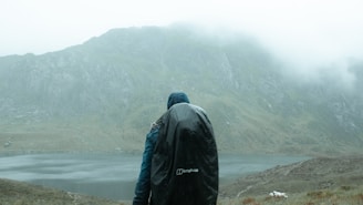 A lightweight, waterproof jacket hanging on a rugged mountain trail with misty peaks in the background.