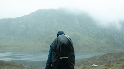A lightweight, waterproof jacket hanging on a rugged mountain trail with misty peaks in the background.