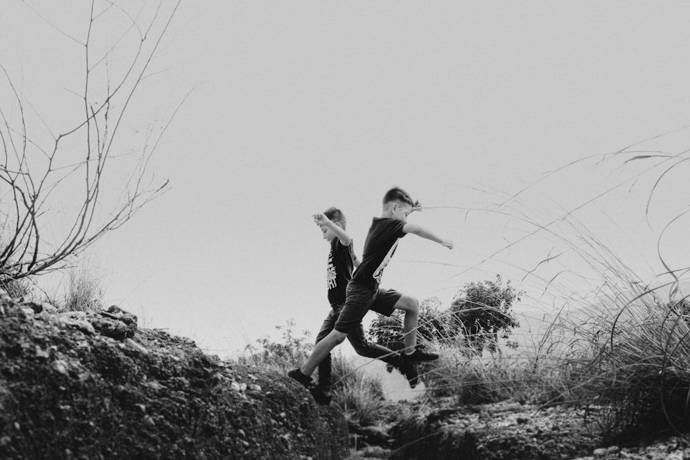 grayscale photo of woman in black long sleeve shirt and black pants sitting on rock