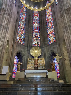 An ornate altar inside a cathedral with stained glass windows casting colorful light.