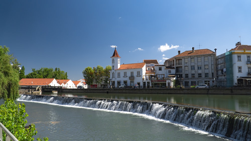 white and brown concrete building near water falls under blue sky during daytime