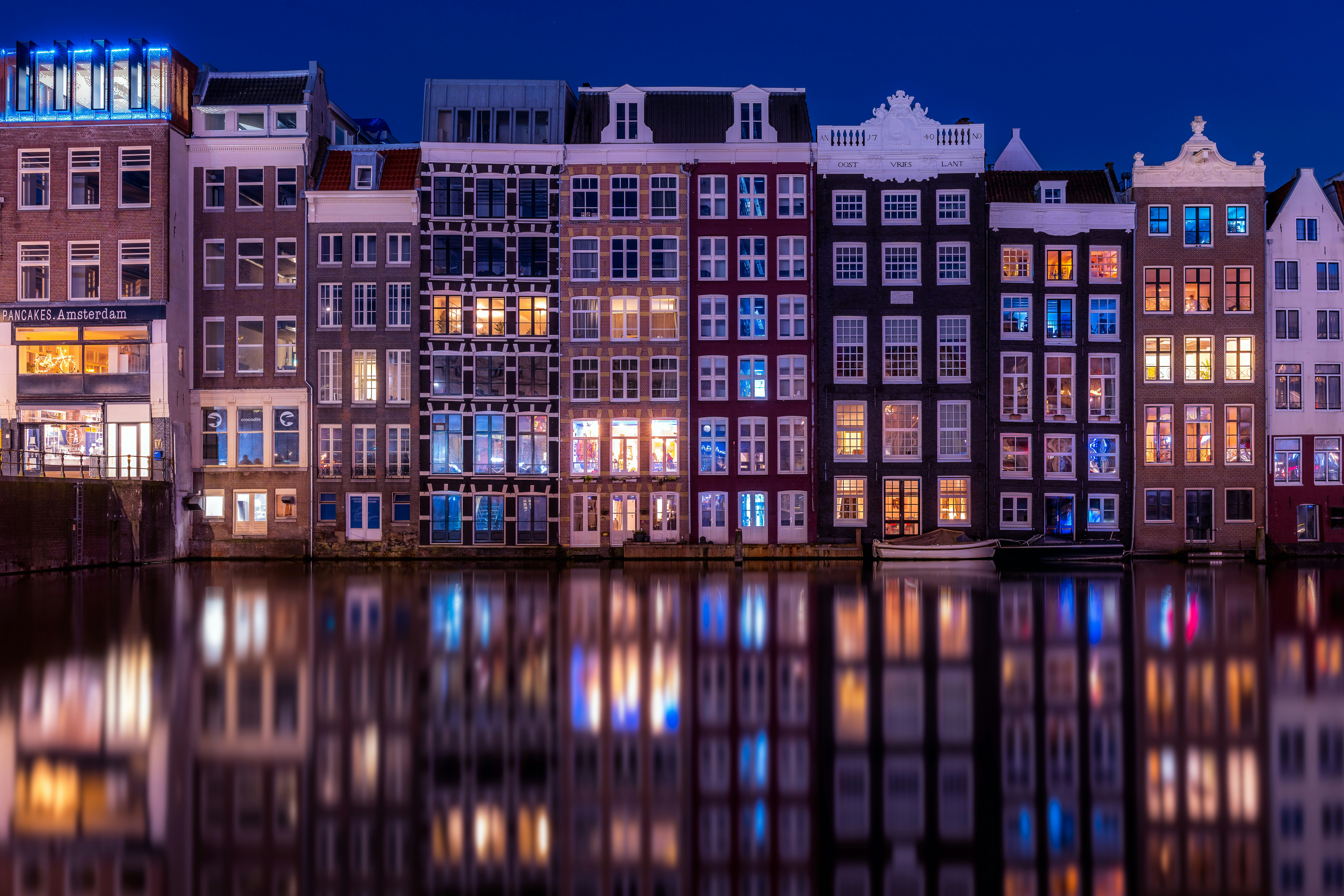 brown and black concrete building during night time, Old warehouses on Damrak in Amsterdam during the bluehour
