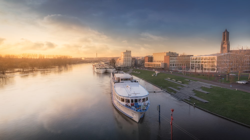 weißes und blaues Boot tagsüber auf dem Wasser in der Nähe von Stadtgebäuden