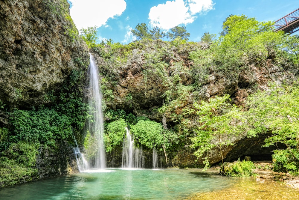 waterfalls in the middle of green trees during daytime