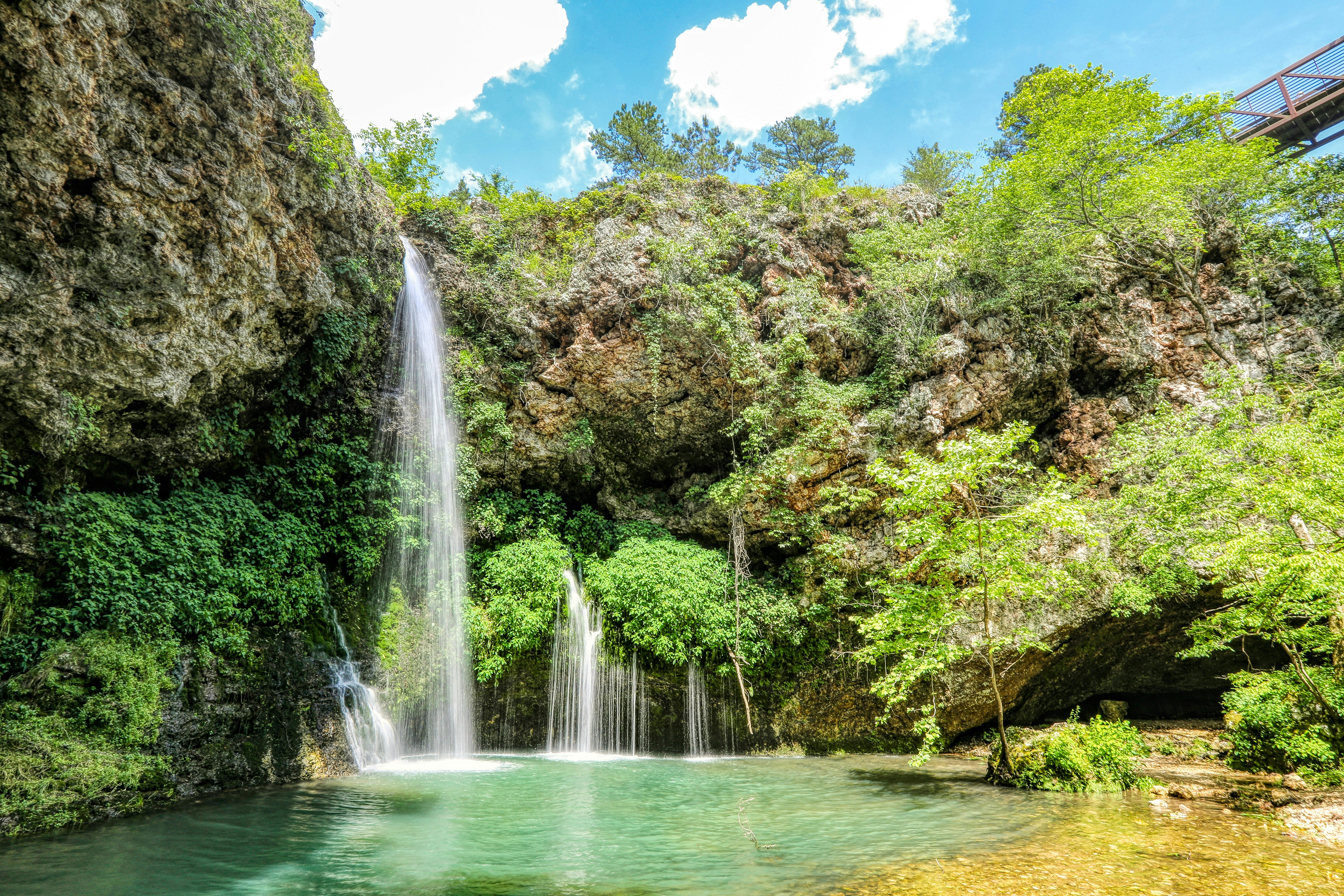 waterfalls in the middle of green trees during daytime