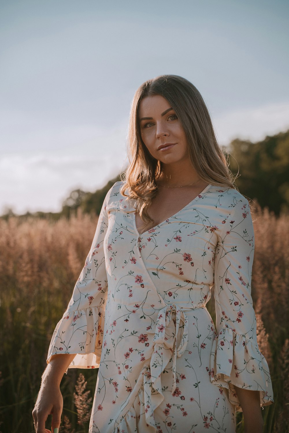 woman in white and red floral long sleeve shirt standing on green grass field during daytime