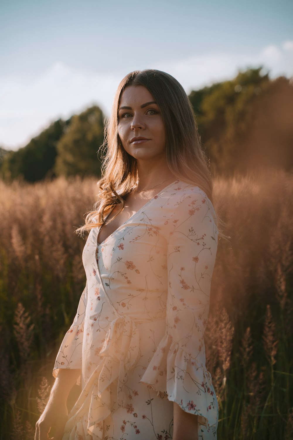 woman in white floral long sleeve shirt standing on brown grass field during daytime