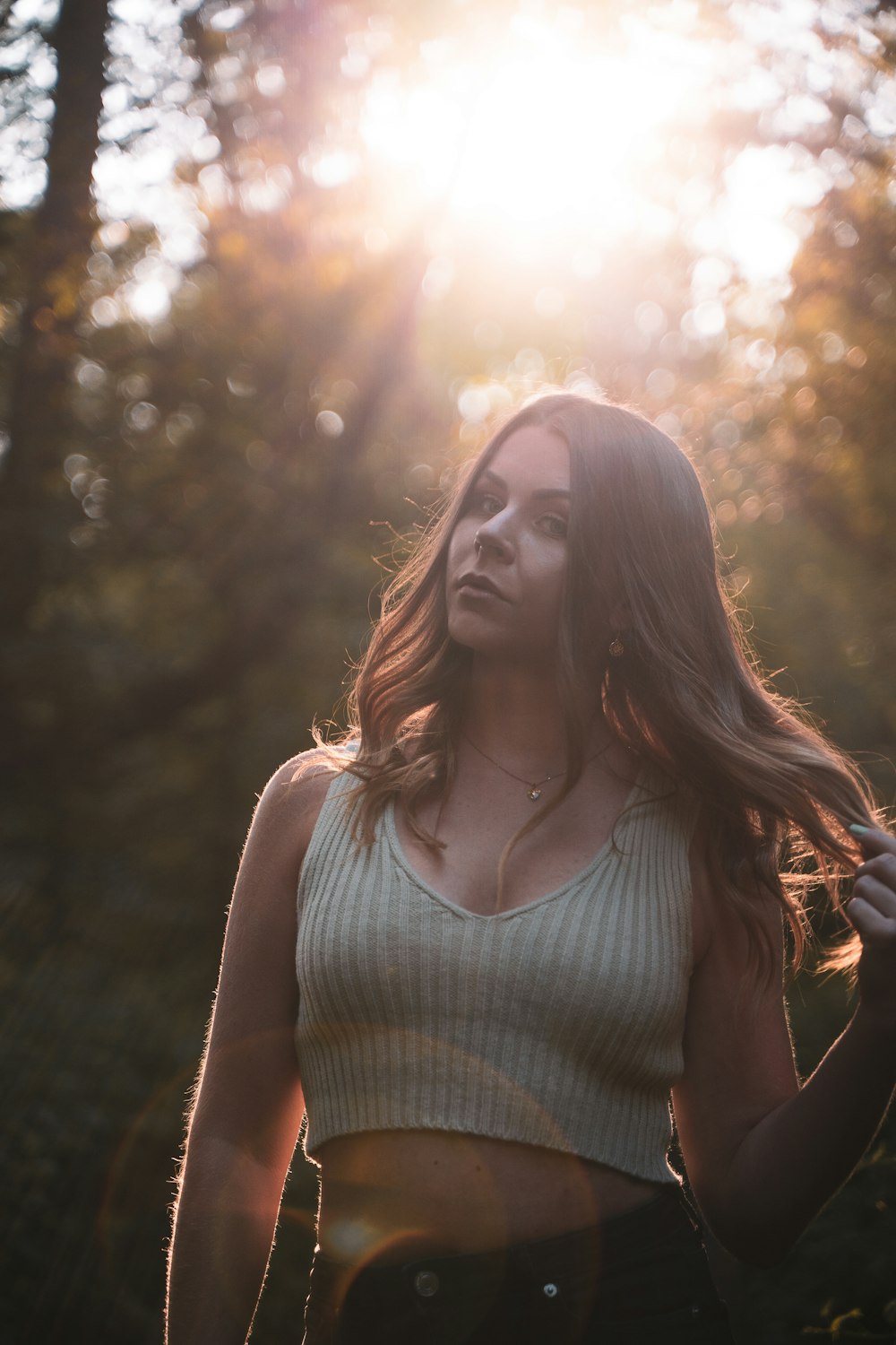 woman in white tank top standing near trees during daytime