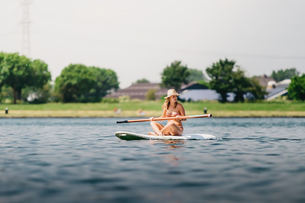 Mujer en bikini marrón montando en kayak verde en el cuerpo de agua durante el día
