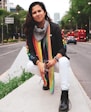 woman in white long sleeve shirt and blue white and black scarf standing on sidewalk during