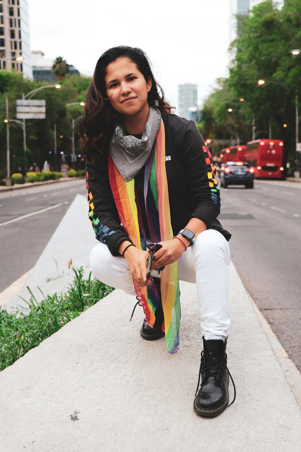 woman in white long sleeve shirt and blue white and black scarf standing on sidewalk during