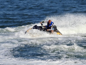 man in blue and red suit riding yellow and black personal watercraft on sea during daytime