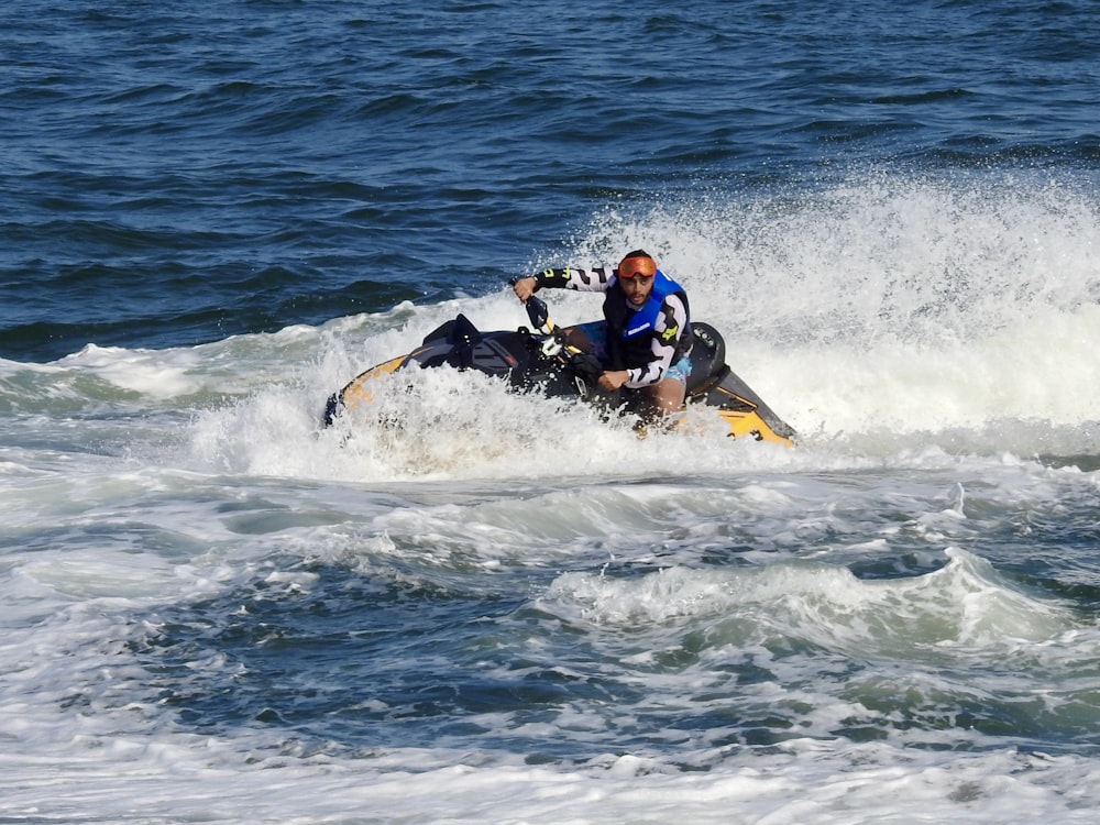 man in blue and red suit riding yellow and black personal watercraft on sea during daytime
