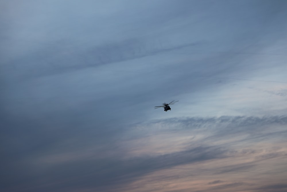 black airplane flying over white clouds during daytime