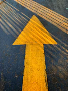 yellow arrow sign on gray concrete road