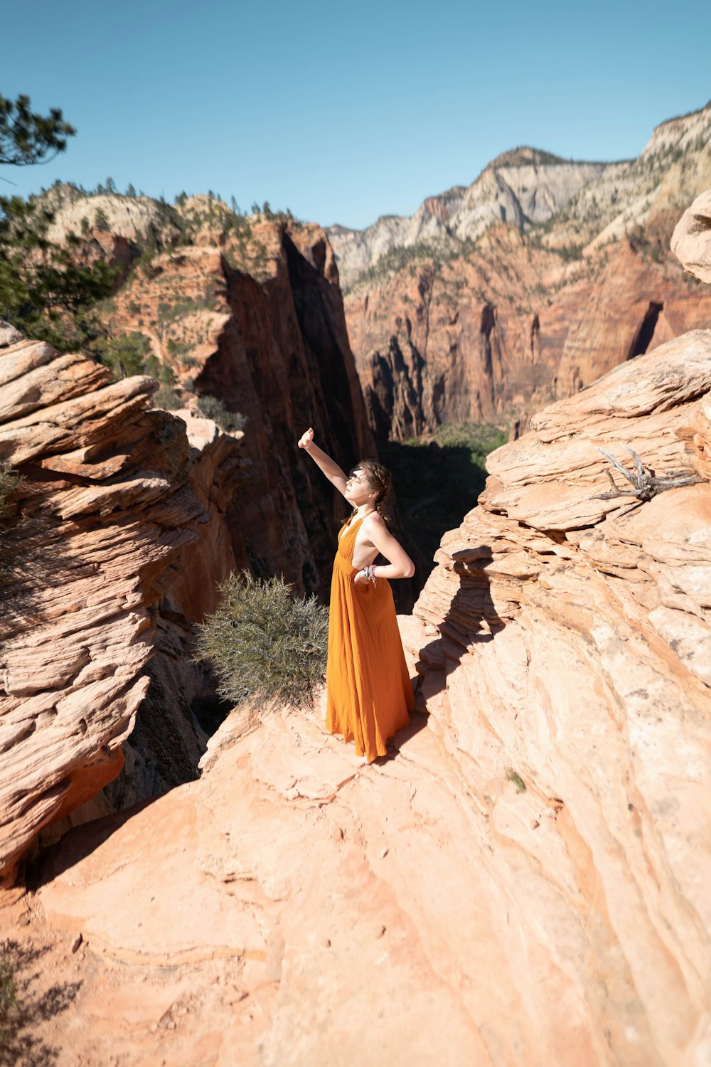 woman in brown dress standing on brown rock formation during daytime