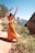 woman in orange dress standing on brown rock formation during daytime