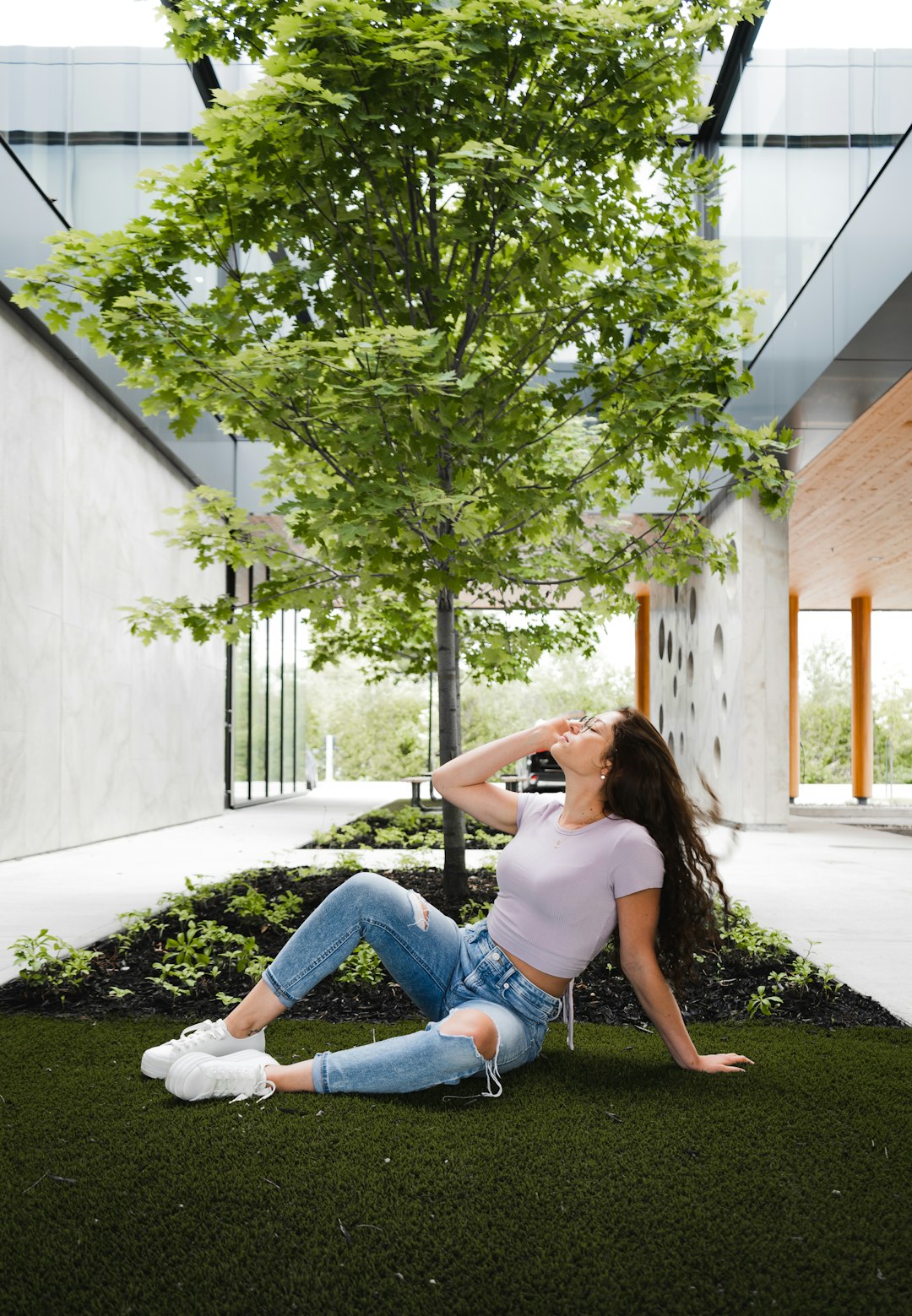 woman in white t-shirt and blue denim jeans sitting on green grass lawn during daytime