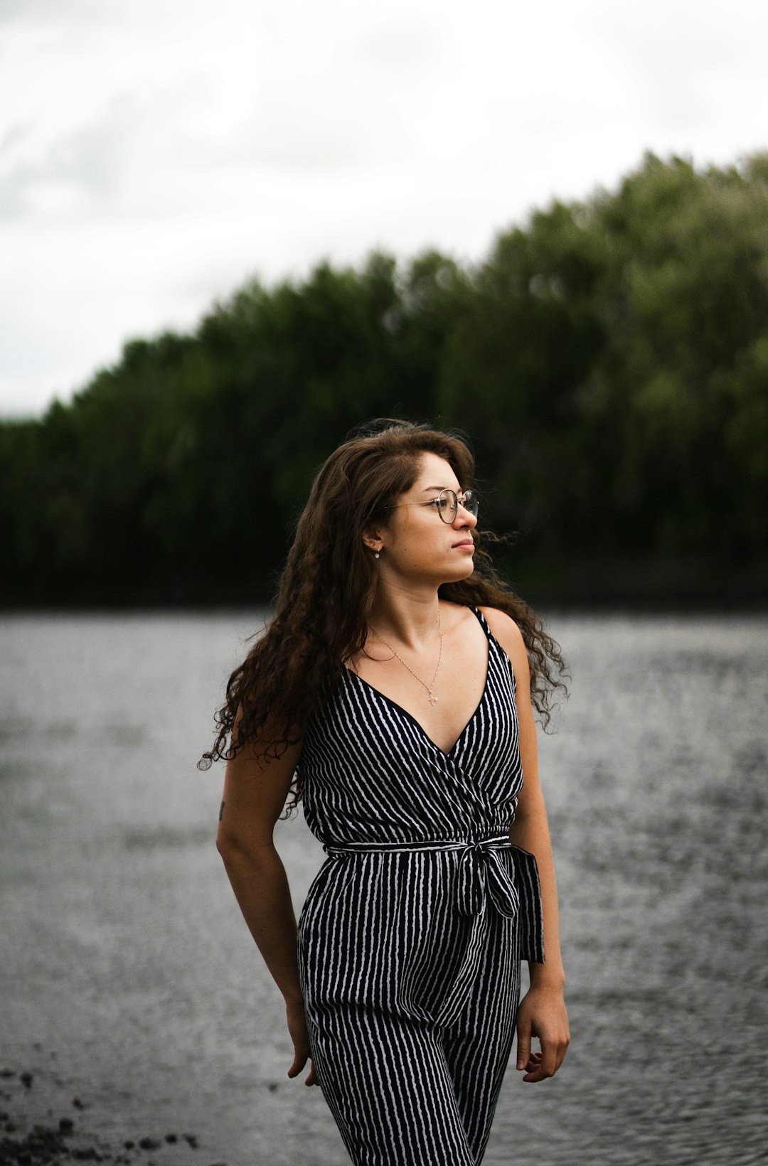 woman in black and white stripe dress standing near body of water during daytime