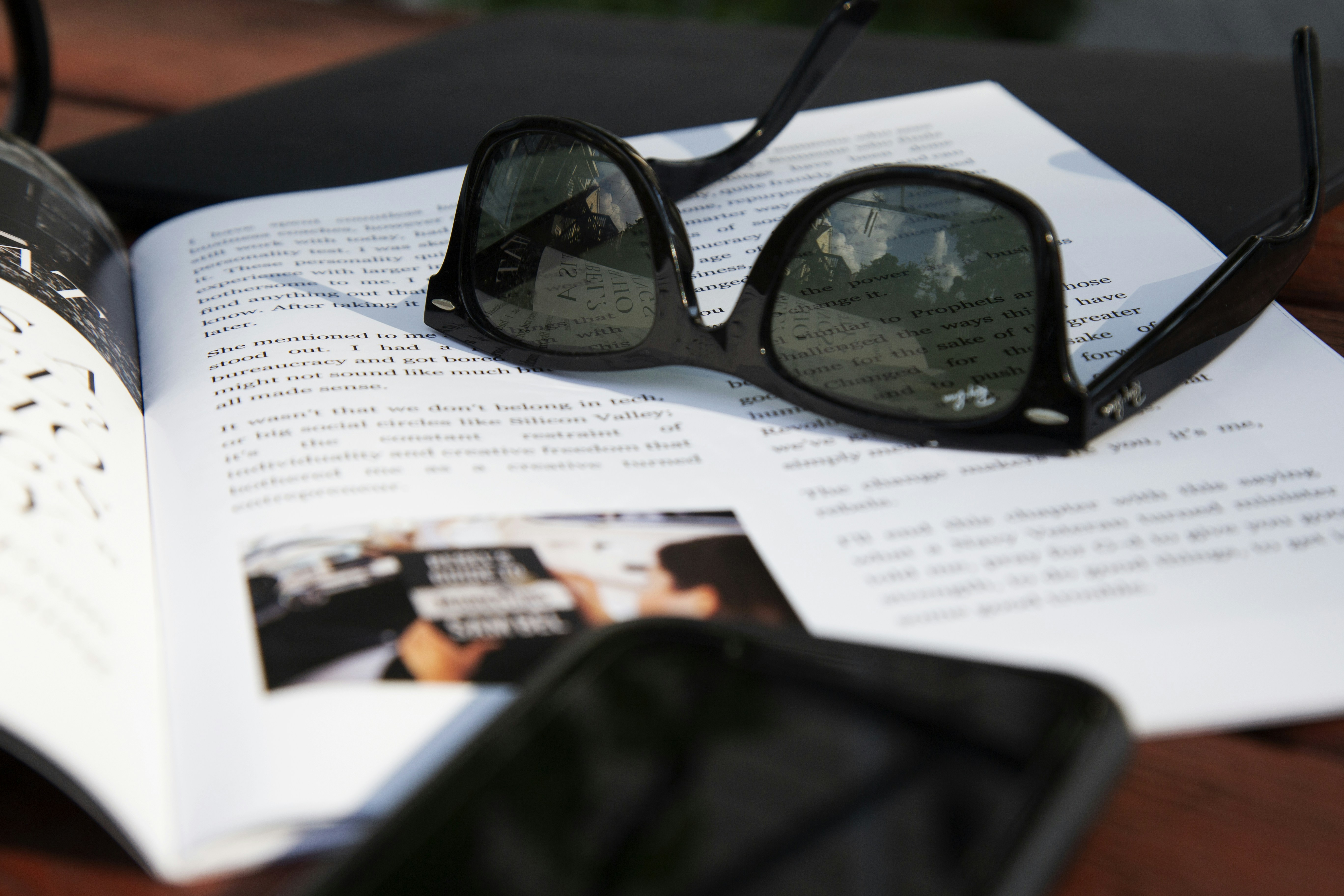 A pair of sunglasses lies atop an open magazine