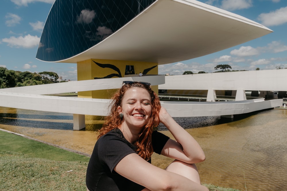 femme en débardeur noir assise sur le champ d’herbe verte pendant la journée