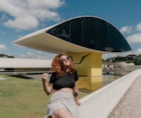 woman in black crop top and white and black striped skirt sitting on white concrete bench