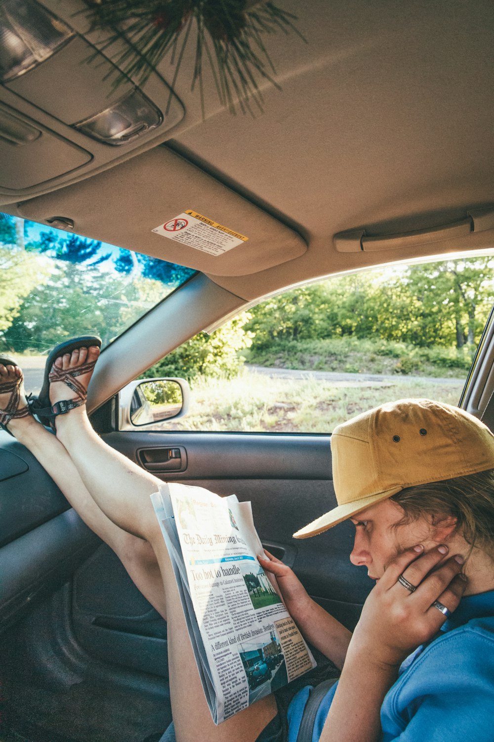 woman in brown sun hat reading book inside car