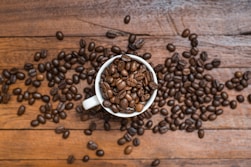 a cup filled with coffee beans on top of a wooden table