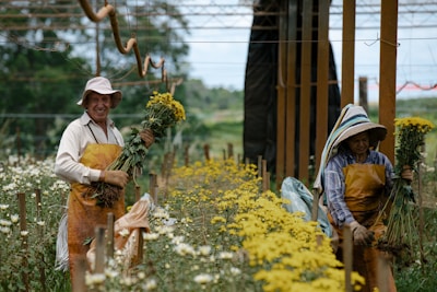 woman in white long sleeve shirt and brown hat standing on yellow flower field during daytime