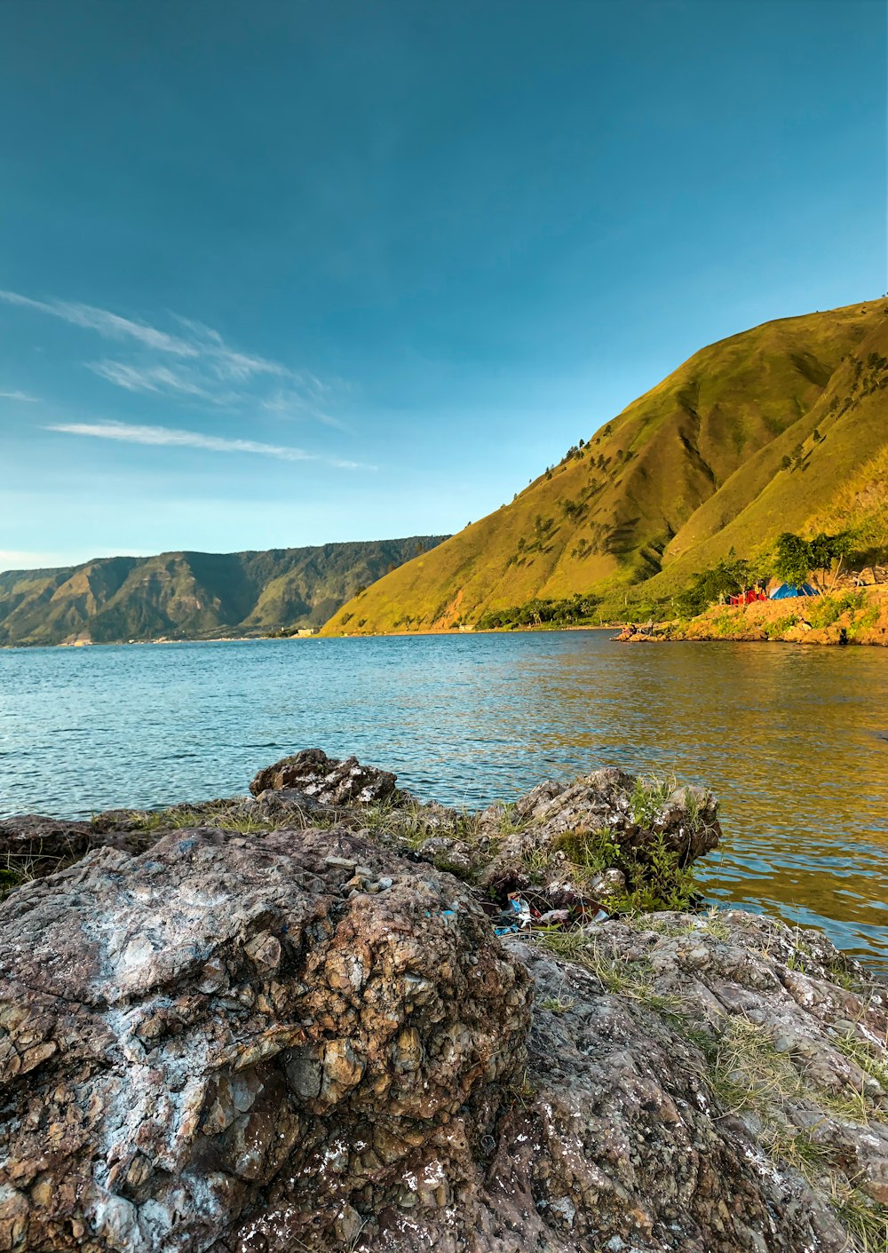 green mountain beside body of water during daytime