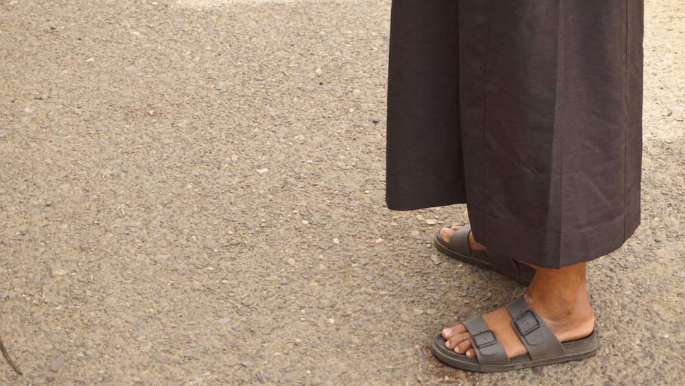 person in black leather sandals