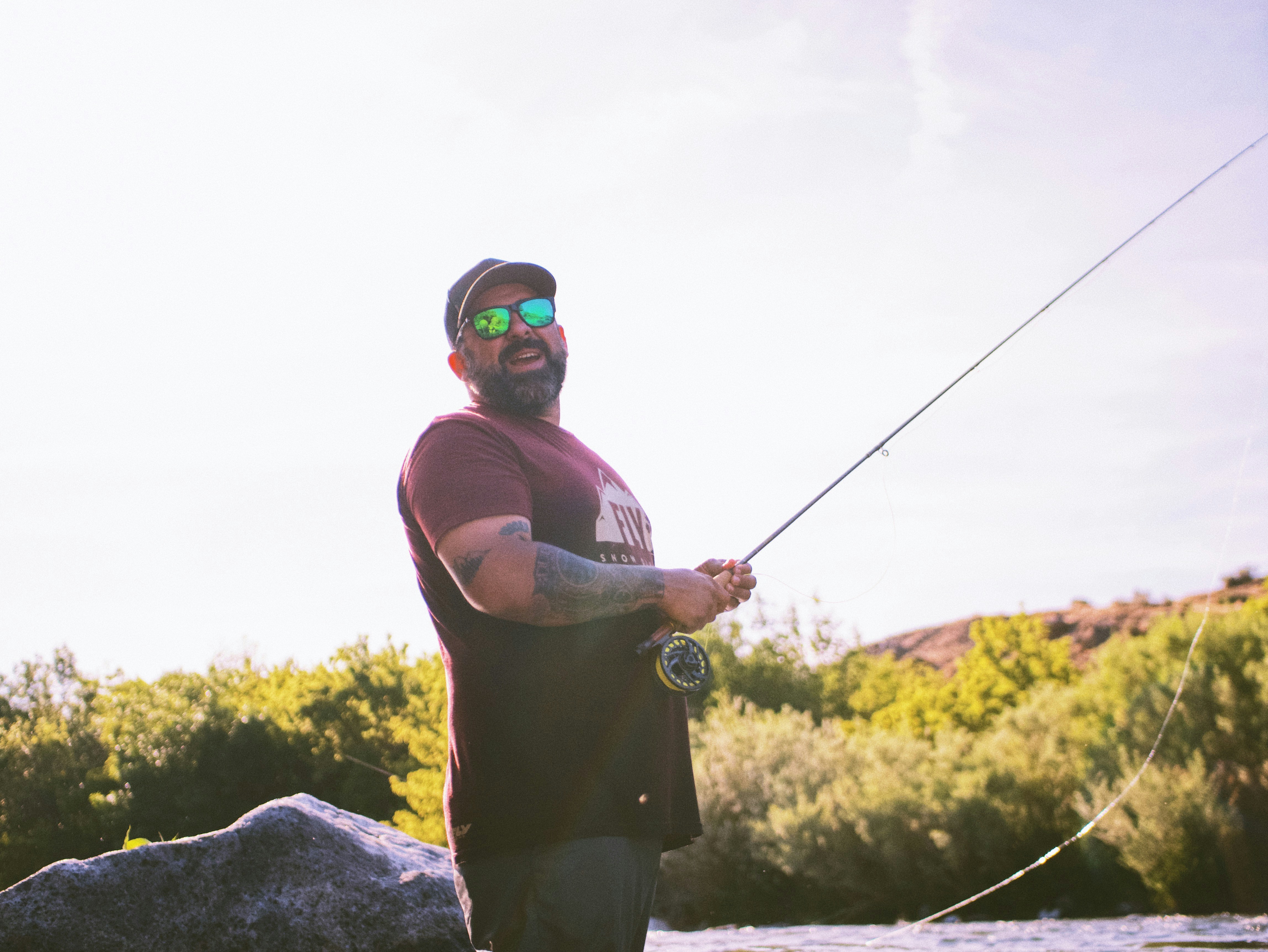 man in red tank top holding fishing rod