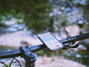 A cyclist riding on a trail with a securely mounted phone holder on the bike handlebar.