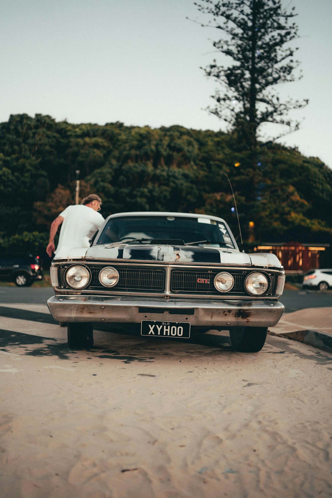 man in white t-shirt standing beside white car during daytime