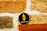 A coin with the Ethereum logo and text rests on a wooden surface against a textured stone wall. The coin has a black background with a gold Ethereum symbol and text.