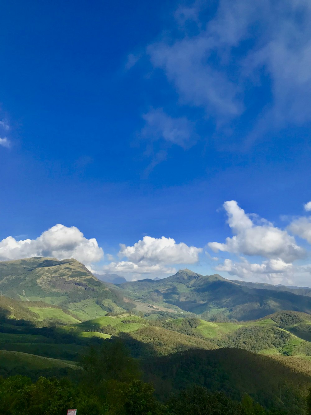 montañas verdes bajo el cielo azul y nubes blancas durante el día