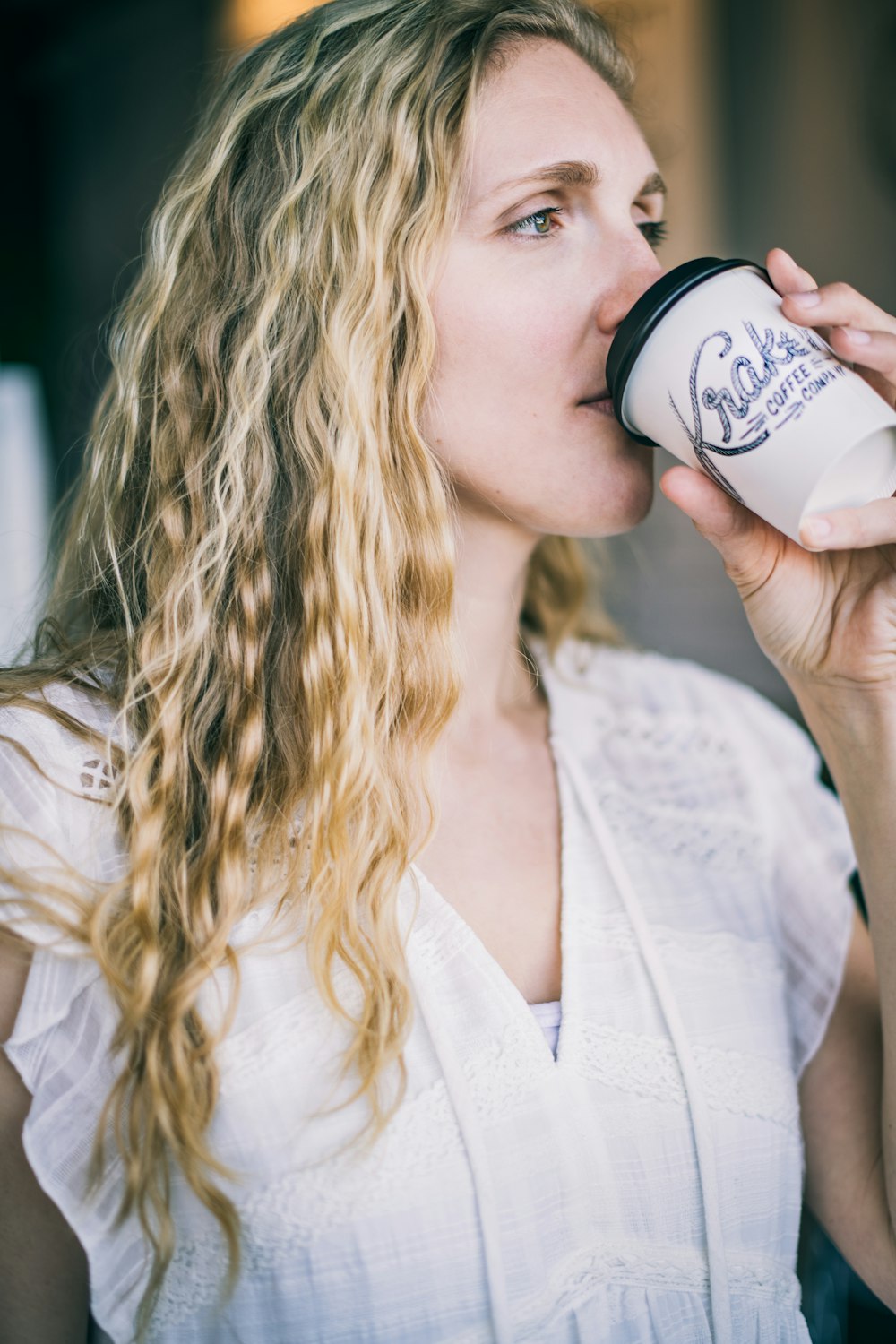 woman in white dress shirt drinking on white ceramic mug