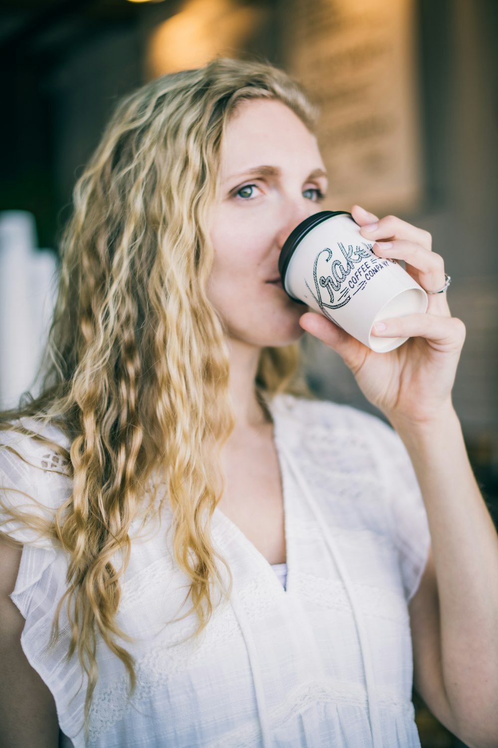 woman in white long sleeve shirt holding white ceramic mug