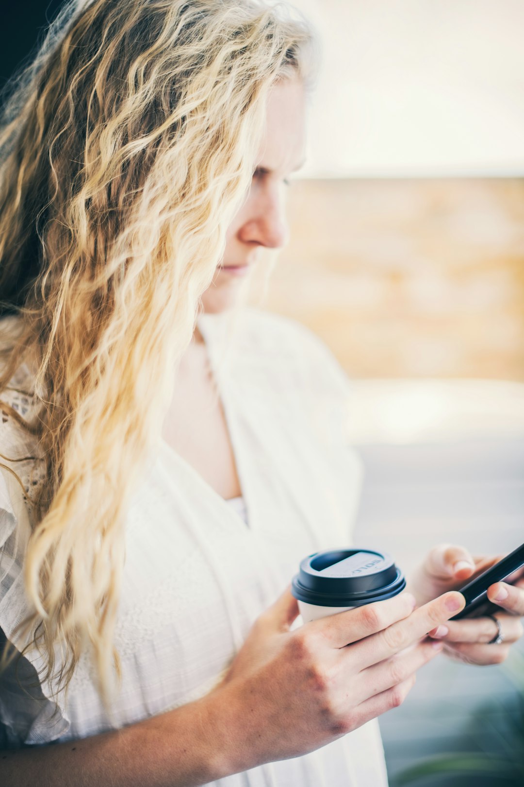 woman in white shirt holding black cup