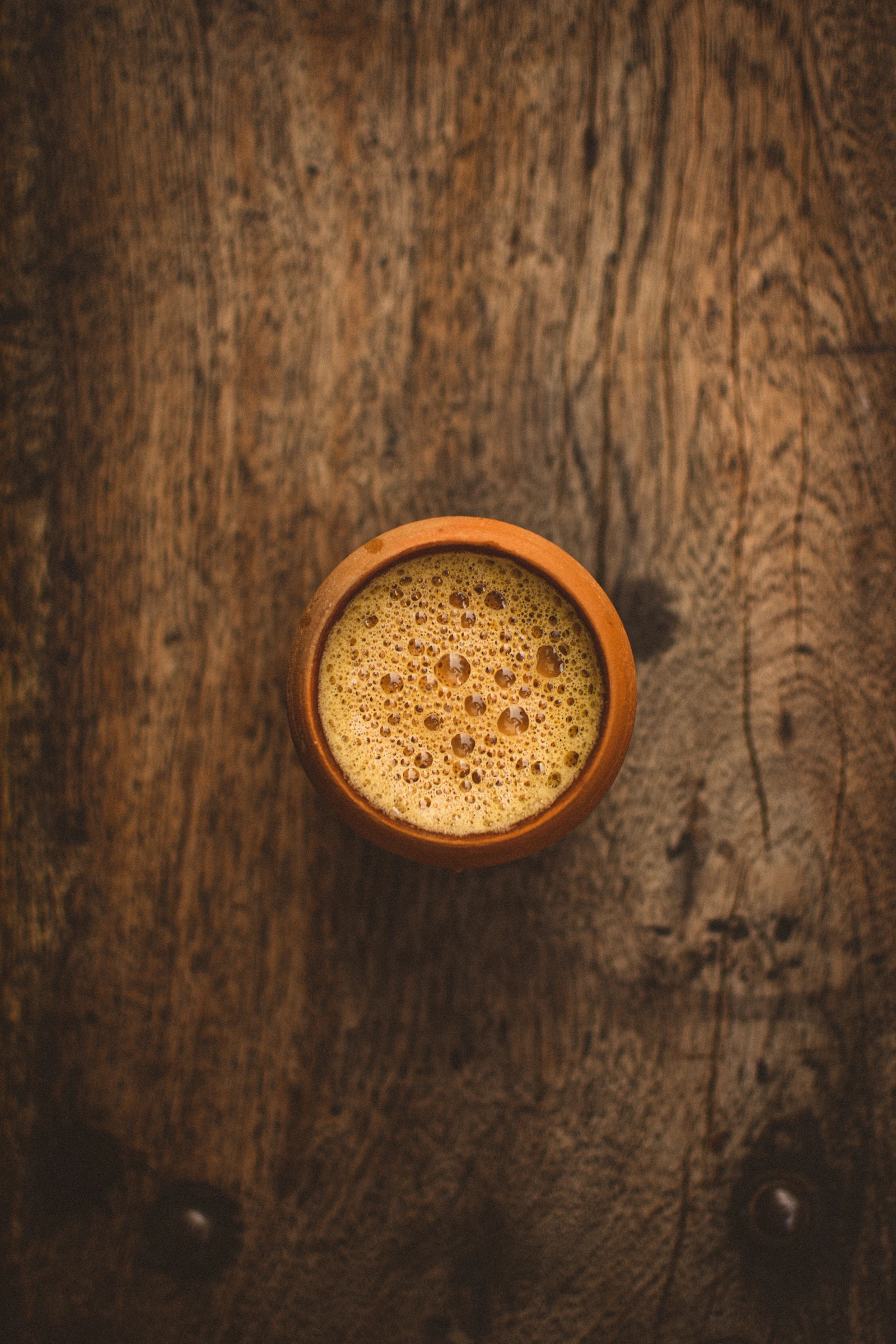 A cup of milky chai on a wooden table, seen from above