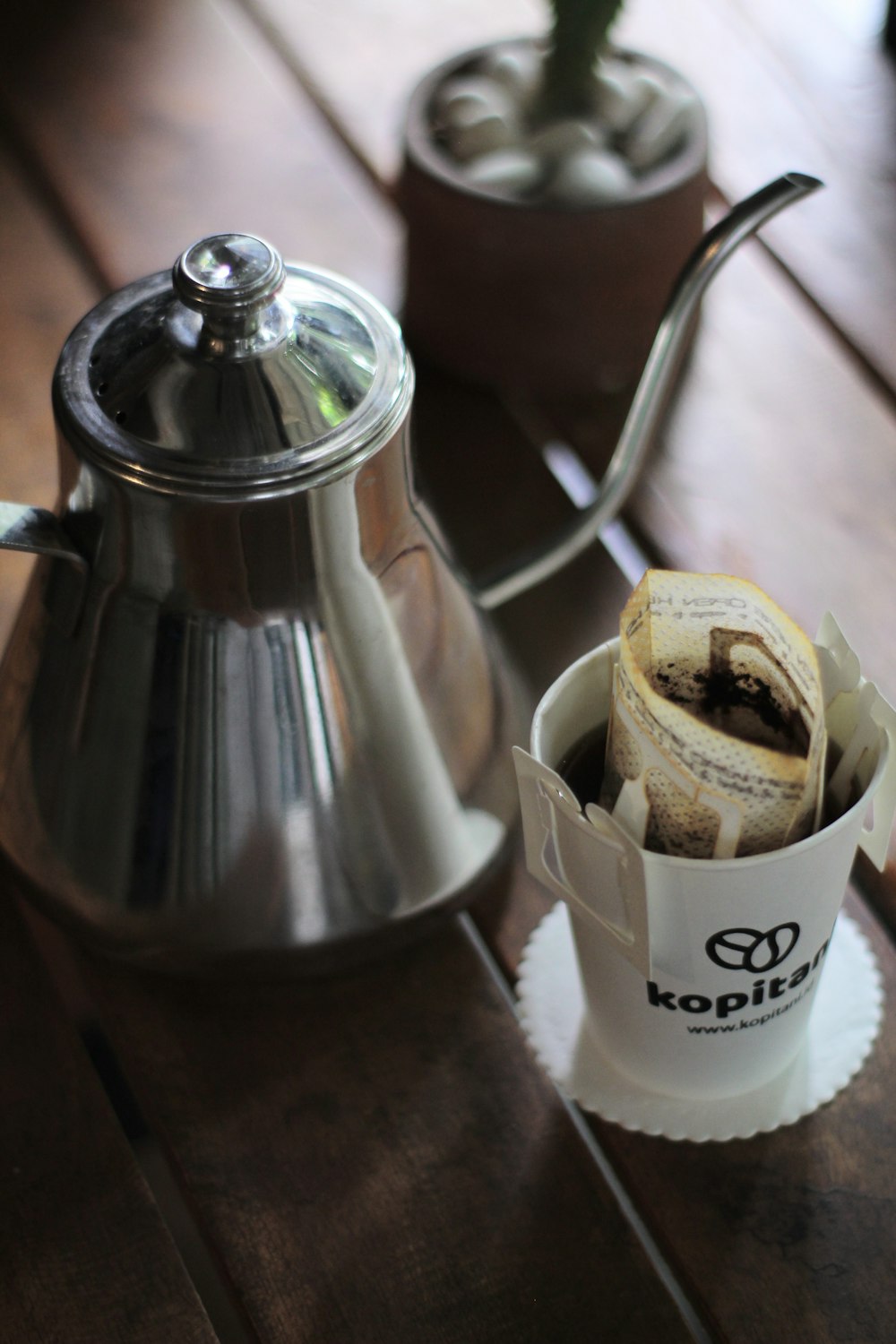 stainless steel teapot beside white ceramic mug