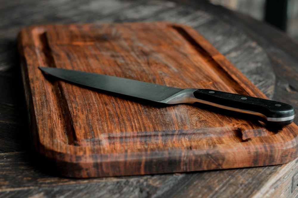 black handled knife on brown wooden chopping board