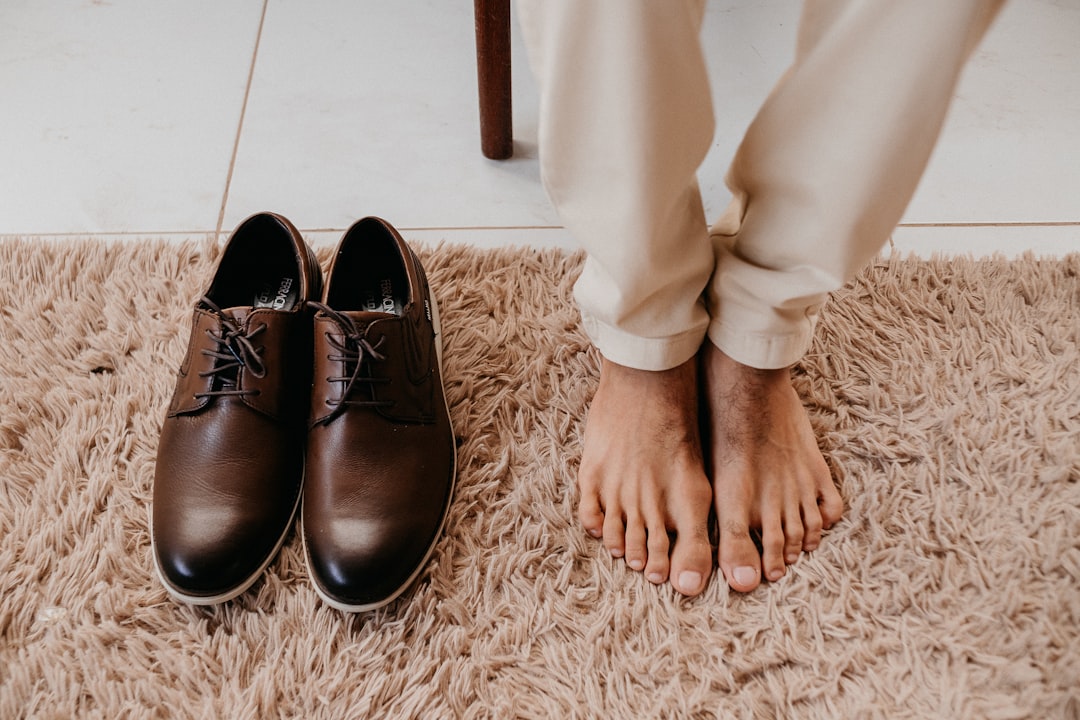 persons feet beside brown leather shoes